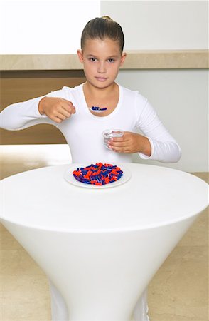 Portrait of Girl Sitting at Table Eating Meal of Pills Stock Photo - Premium Royalty-Free, Code: 600-00934662