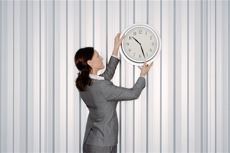 Businesswoman Hanging Clock on Wall Foto de stock - Sin royalties Premium, Código: 600-00933858