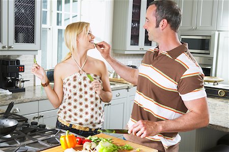 photo of a woman feeding her husband food - Couple Preparing Dinner Stock Photo - Premium Royalty-Free, Code: 600-00947978