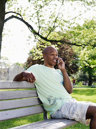 Man Sitting on Park Bench Using Cellular Telephone Fotografie stock - Premium Royalty-Free, Codice: 600-00948557