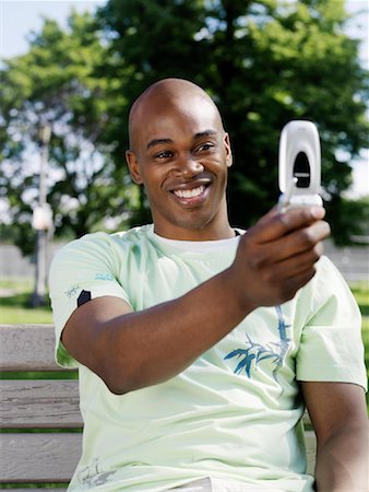 Man Sitting on Park Bench Taking Picture Foto de stock - Royalty Free Premium, Número: 600-00948558