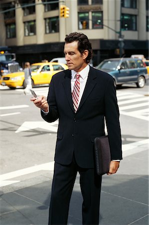 Businessman using Cellular Phone on Sidewalk Stock Photo - Premium Royalty-Free, Code: 600-00948891