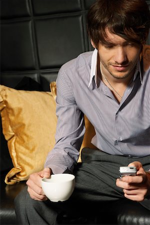 Businessman in Hotel Lobby with Cellular Phone and Coffee Stock Photo - Premium Royalty-Free, Code: 600-00984348