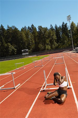 pictures of athletes falling down - Woman Sitting on Running Track after Stumbling Stock Photo - Premium Royalty-Free, Code: 600-01037112