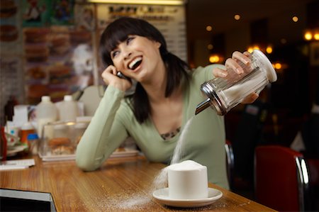Woman Distracted by Phone Call, Filling Cup with Sugar Foto de stock - Sin royalties Premium, Código: 600-01042093