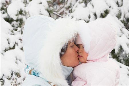 Mother Kissing Baby Daughter in Snowsuit Foto de stock - Sin royalties Premium, Código: 600-01073724