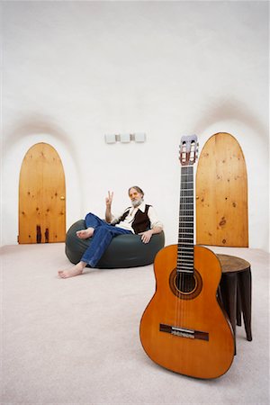 Man Sitting in Bean Bag Chair with Guitar in Foreground Stock Photo - Premium Royalty-Free, Code: 600-01083730