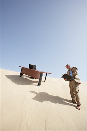 Homme d'affaires de lecture du fichier de bureau dans le désert Photographie de stock - Premium Libres de Droits, Code: 600-01109996