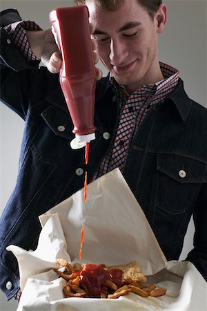 french fry smile - Man Pouring Ketchup on Fish and Chips Stock Photo - Premium Royalty-Free, Code: 600-01110097