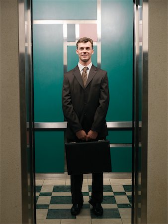 smiling businessman in elevator - Businessman in Elevator Stock Photo - Premium Royalty-Free, Code: 600-01124213
