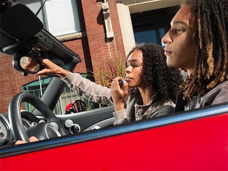 Woman Putting on Lipstick While Boyfriend Drives Foto de stock - Sin royalties Premium, Código: 600-01164683