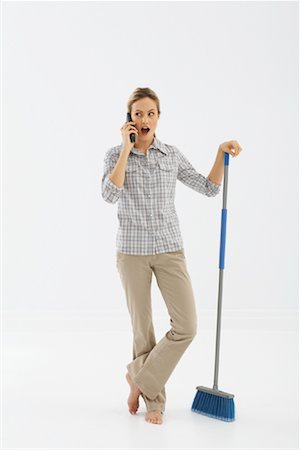 Woman Using Cellular Phone and Holding Broom Stock Photo - Premium Royalty-Free, Code: 600-01172791