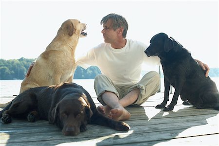 simsearch:600-02265288,k - Man With Dogs, Sitting on Dock Foto de stock - Sin royalties Premium, Código: 600-01183024