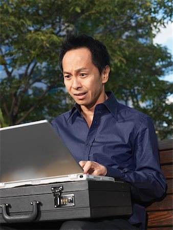 scared asian man - Man on Park Bench Using Laptop Computer Stock Photo - Premium Royalty-Free, Code: 600-01194866