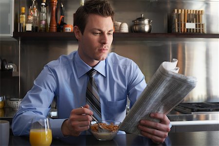 Man Reading Newspaper During Breakfast Stock Photo - Premium Royalty-Free, Code: 600-01235444