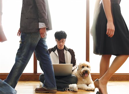 People Walking Past Man Sitting On Floor Using Laptop Stock Photo - Premium Royalty-Free, Code: 600-01248268