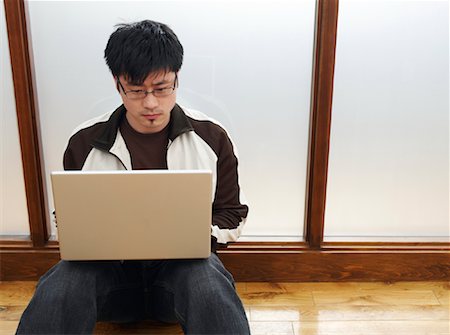 Homme assis sur le plancher à l'aide d'ordinateur portable Photographie de stock - Premium Libres de Droits, Code: 600-01248261