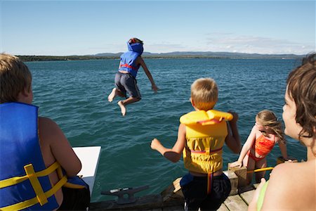 Enfants en sautant dans le lac des gilets de sauvetage Photographie de stock - Premium Libres de Droits, Code: 600-01248831