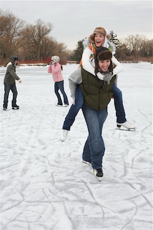 friends playing in snow - Man Giving Woman Piggyback Ride On Ice Foto de stock - Sin royalties Premium, Código: 600-01249416