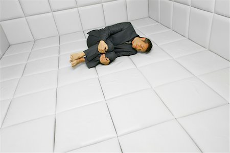 Man in Fetal Position in Padded Room Foto de stock - Sin royalties Premium, Código: 600-01407174