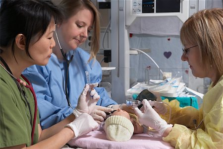 side images of dark hair nurse in uniform - Nurses Practicing on Baby Mannequin Stock Photo - Premium Royalty-Free, Code: 600-01595848
