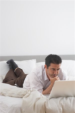 Man Using Laptop on Bed Stock Photo - Premium Royalty-Free, Code: 600-01604085