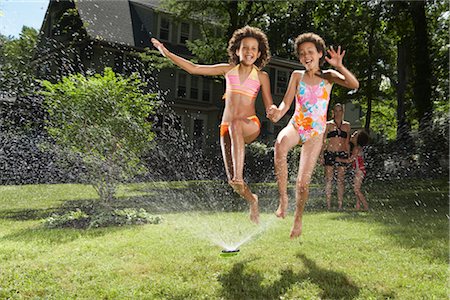 running sprinkler - Family playing in backyard with sprinkler Stock Photo - Premium Royalty-Free, Code: 600-01614312