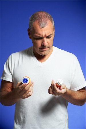 rimedio contro il dolore - Man Looking at Pill Containers Fotografie stock - Premium Royalty-Free, Codice: 600-01613461