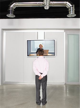 Businessman Videoconferencing with Big Screen Television Stock Photo - Premium Royalty-Free, Code: 600-01695645