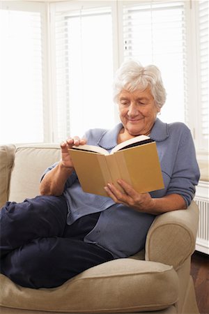 Senior Woman Sitting on Sofa Reading Book Stock Photo - Premium Royalty-Free, Code: 600-01716151