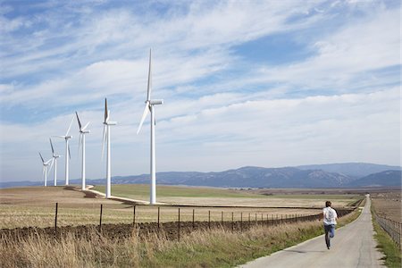 simsearch:600-06431301,k - Garçon en cours d'exécution sur Raod Rural, à proximité des éoliennes Photographie de stock - Premium Libres de Droits, Code: 600-01742840