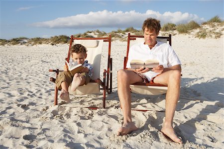 dad reads to children the book in the chair - Father and Son Reading on Beach, Majorca, Spain Stock Photo - Premium Royalty-Free, Code: 600-01764765