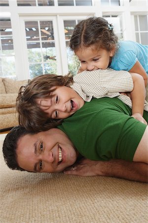 family looking at camera indoor - Father and Kids Play Fighting Stock Photo - Premium Royalty-Free, Code: 600-01787581