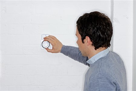 posing and back and one man - Man Adjusting Thermostat Stock Photo - Premium Royalty-Free, Code: 600-01956117