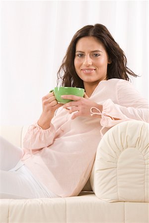 simsearch:600-02033682,k - Femme sur le canapé avec une tasse de café Photographie de stock - Premium Libres de Droits, Code: 600-02010014