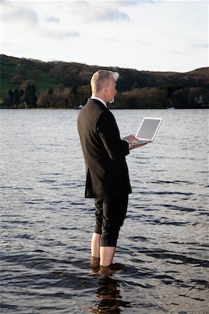 Homme d'affaires avec ordinateur portable debout dans le lac Windermere, Cumbria, Angleterre Photographie de stock - Premium Libres de Droits, Code: 600-02010369