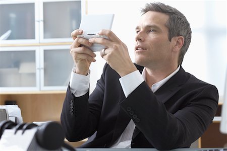 simsearch:600-02081714,k - Businessman Playing Handheld Video Game at Desk Stock Photo - Premium Royalty-Free, Code: 600-02081705