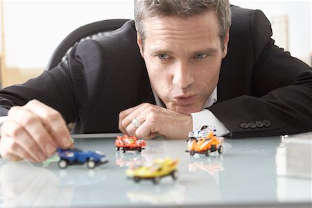 Businessman Playing with Toy Race Cars on Desk Foto de stock - Sin royalties Premium, Código: 600-02081700