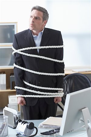 simsearch:600-02081724,k - Businessman Tied Up with Rope at Desk Stock Photo - Premium Royalty-Free, Code: 600-02081764