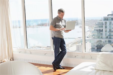 simsearch:600-02130675,k - Man with Laptop in Condominium Stock Photo - Premium Royalty-Free, Code: 600-02130673