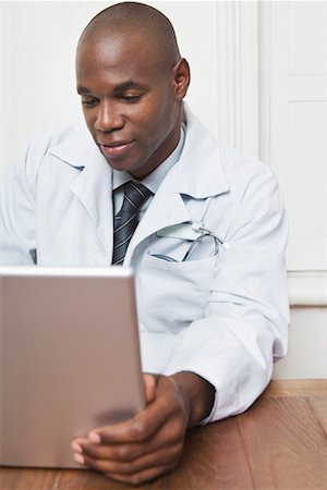 Physician Sitting Behind Desk Working on Laptop Stock Photo - Premium Royalty-Free, Code: 600-02201175