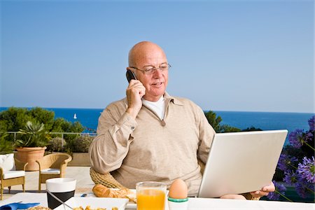 Man on Patio Eating Breakfast, Using Laptop Computer and Talking on Cellular Phone Photographie de stock - Premium Libres de Droits, Code: 600-02290215