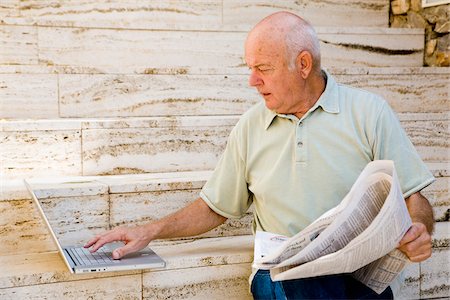 Man Reading Newspaper and Using Laptop Computer Stock Photo - Premium Royalty-Free, Code: 600-02290225