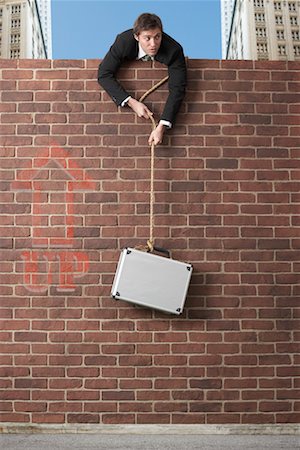 escaping (liberate from capture) - Businessman Lowering Briefcase Over Brick Wall Stock Photo - Premium Royalty-Free, Code: 600-02312389