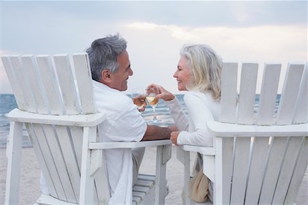 Couple Toasting with Wine while Sitting on Chairs on Beach Stock Photo - Premium Royalty-Free, Code: 600-02346334