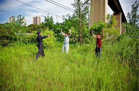 Police Officer Arresting Two Men in a Grassy Field Foto de stock - Sin royalties Premium, Código: 600-02348041