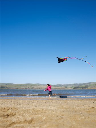 people flying kites in the sky - Girl Flying Kite on Beach Stock Photo - Premium Royalty-Free, Code: 600-02637683