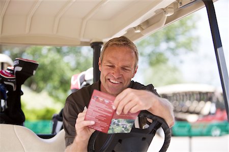 Man with Score Card in Golf Cart Foto de stock - Royalty Free Premium, Número: 600-02670417