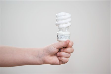 simsearch:600-06334349,k - Child's Hand Holding Energy Efficient Bulb Fotografie stock - Premium Royalty-Free, Codice: 600-02702743