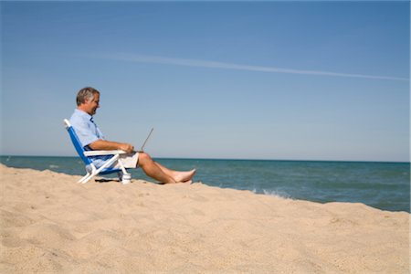 Man Sitting on the Beach Using Laptop Computer, Lake Michigan, USA Foto de stock - Royalty Free Premium, Número: 600-02757025